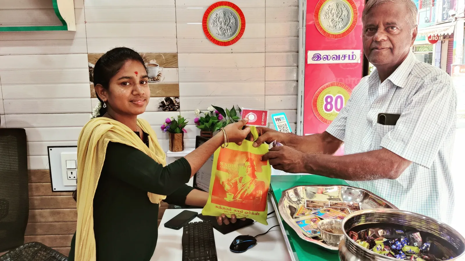 A Sundaram Coffee Works cloth bag being handed across the shop counter