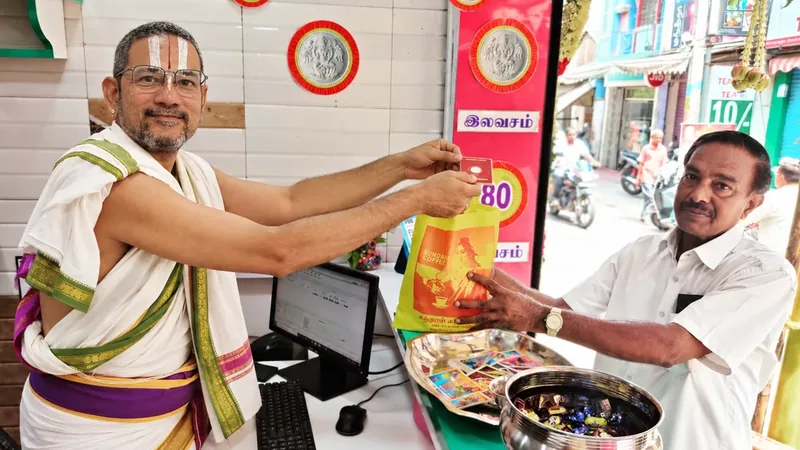 Rajagopalan N. behind the counter of Sundaram Coffee Works, handing a packet across