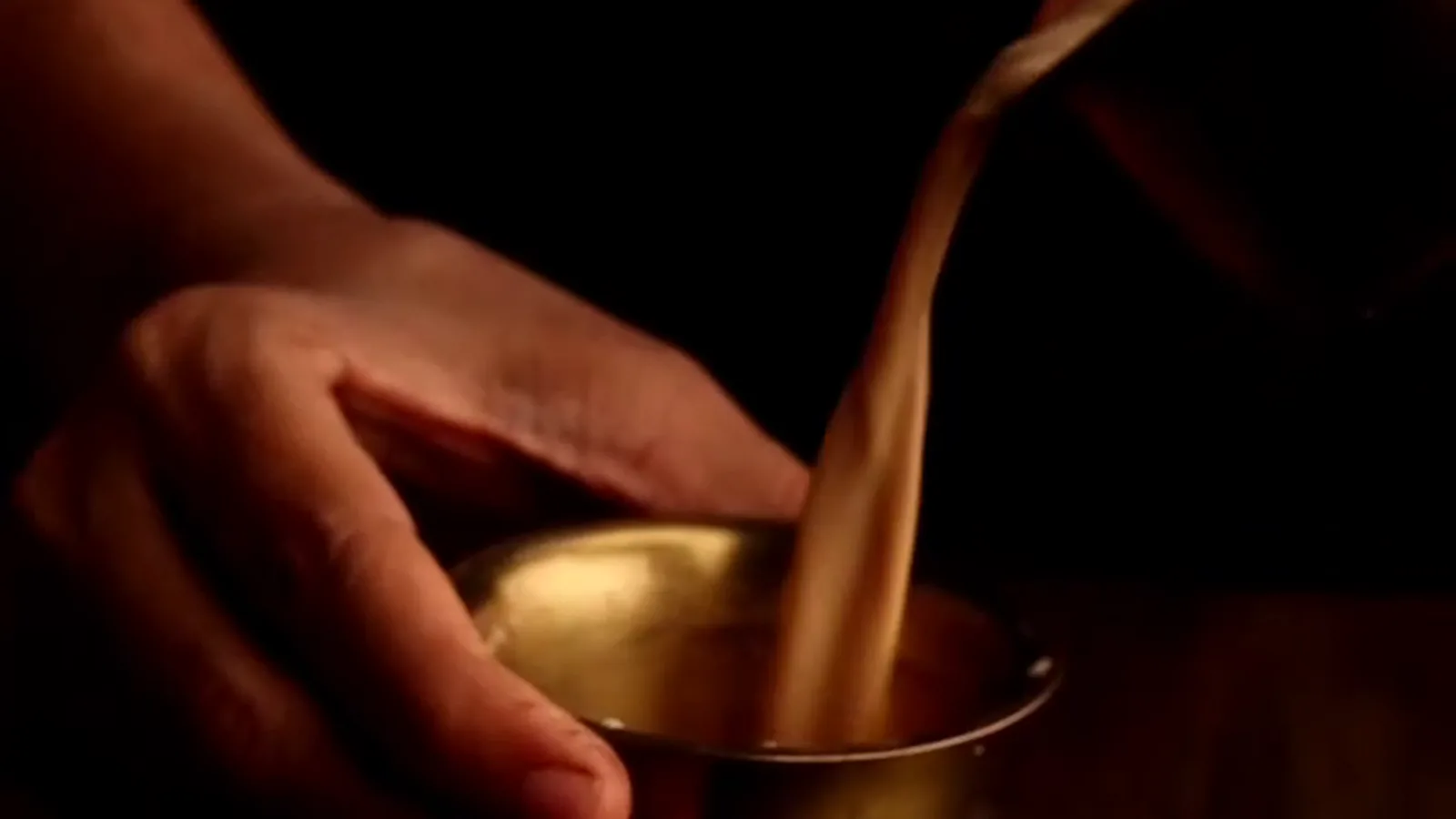 Coffee poured by hand into a brass tumbler